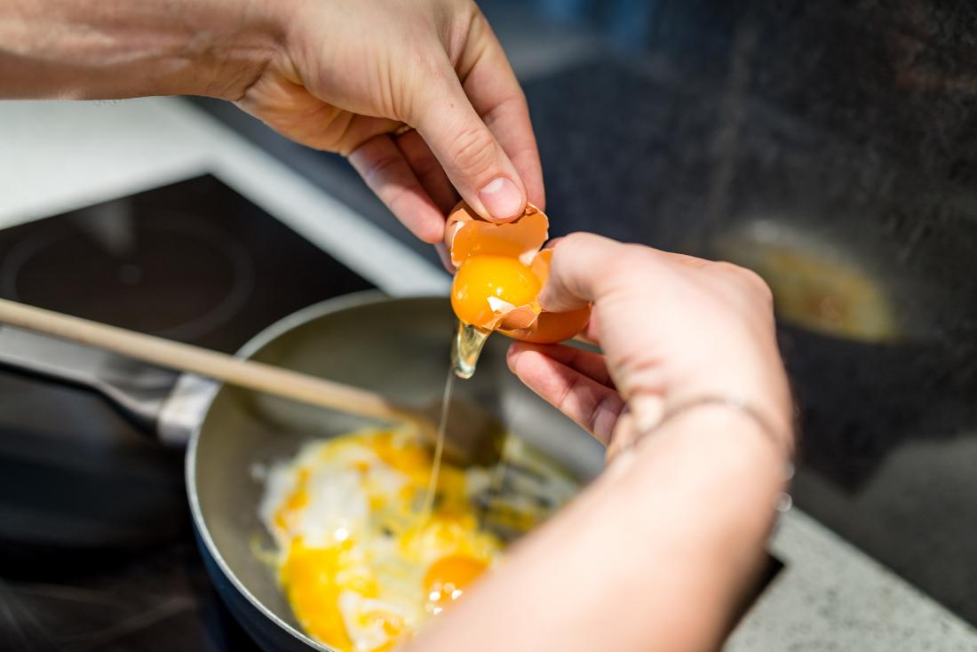 close up of hands preparing eggs in a pan