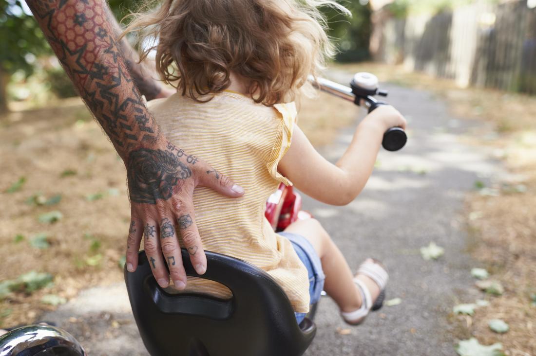 A child on a bike getting pushed along.