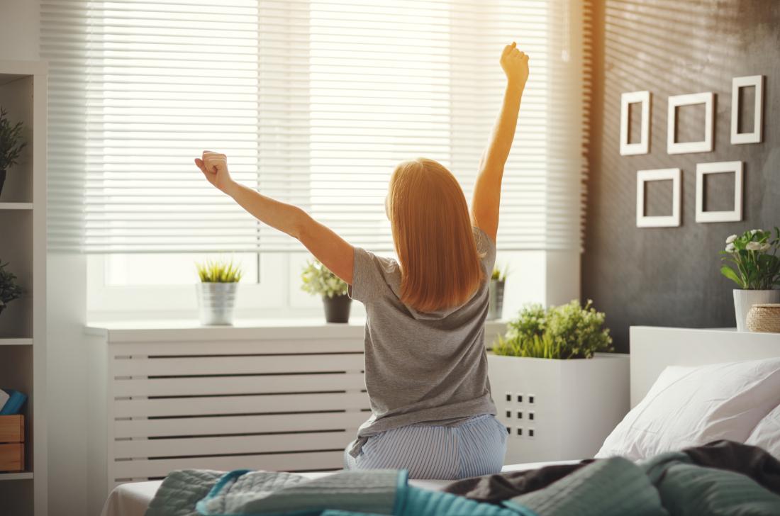 woman waking up stretching, seen from behind