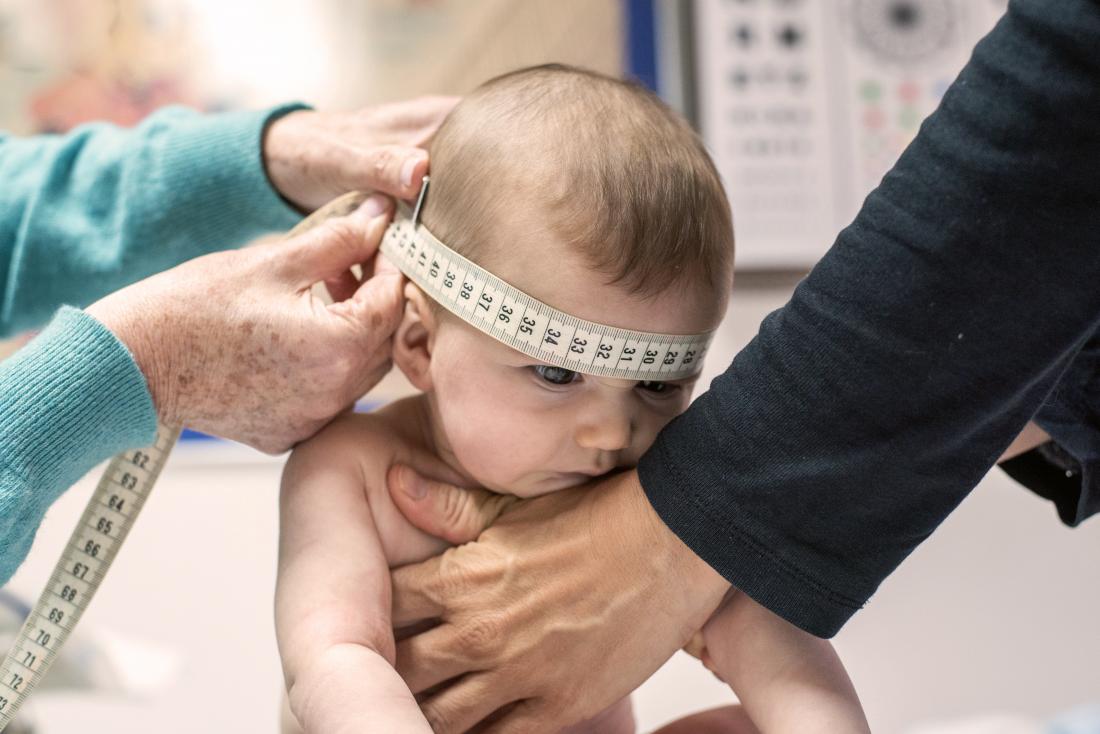 A baby getting the circumference of its head measured. 