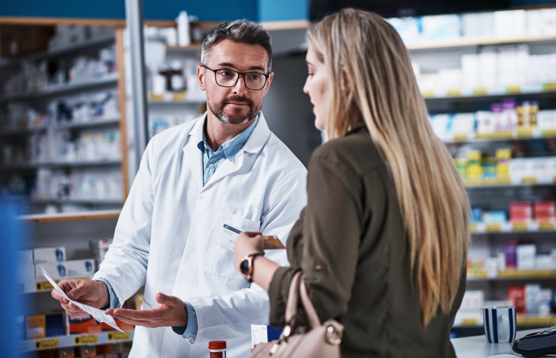 A woman speaking to a male pharmacist. 