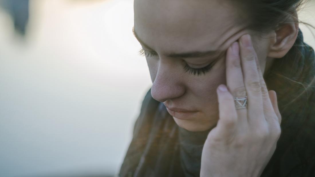 woman massaging the left side of her head because she has a headache