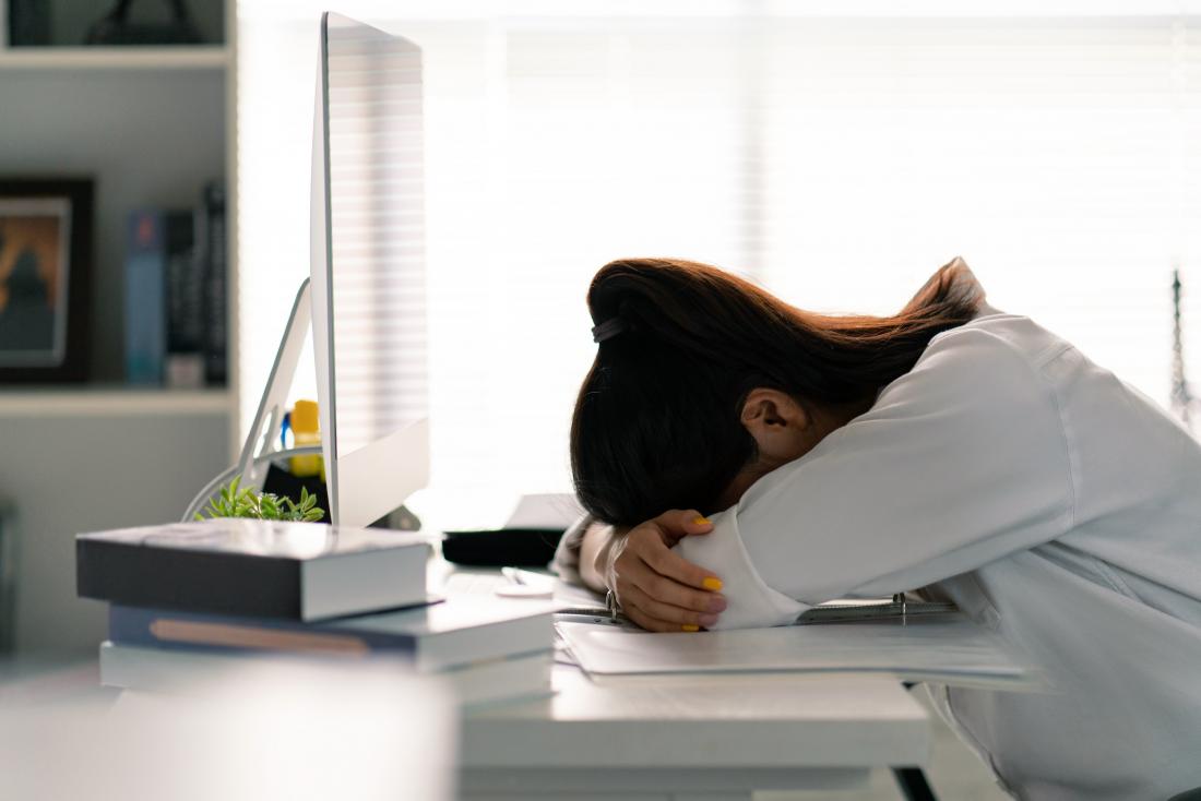A woman suffering from extreme tiredness at her work desk.