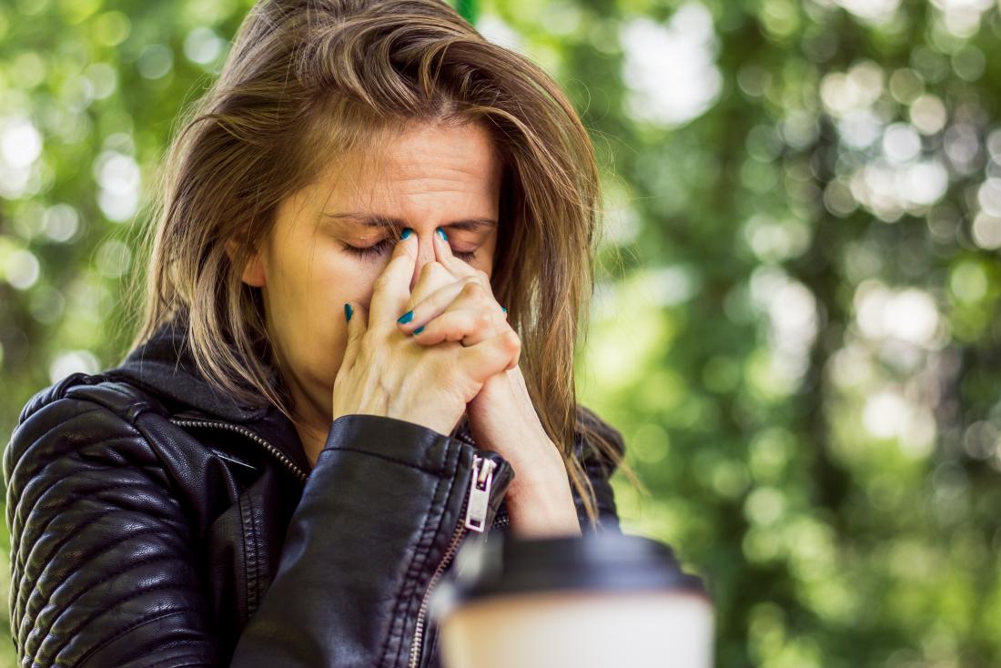 A woman with a sore nose holding her nose with her fingers.