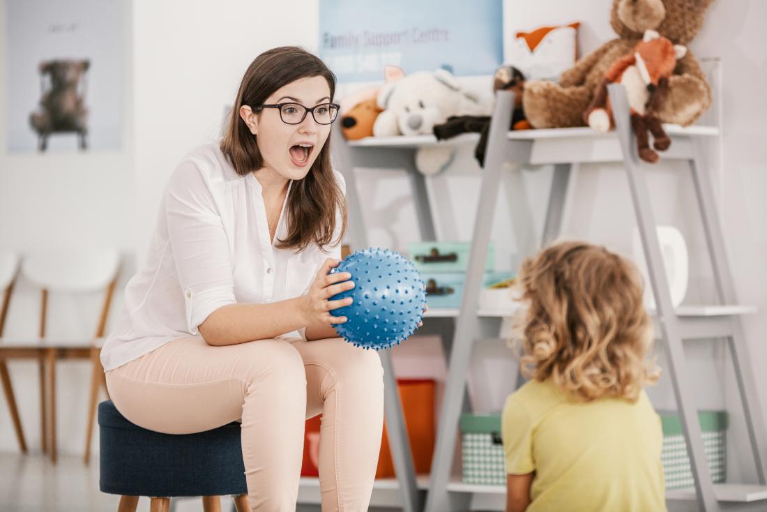 A sensory game with a blue ball played by a professional child therapist with a child