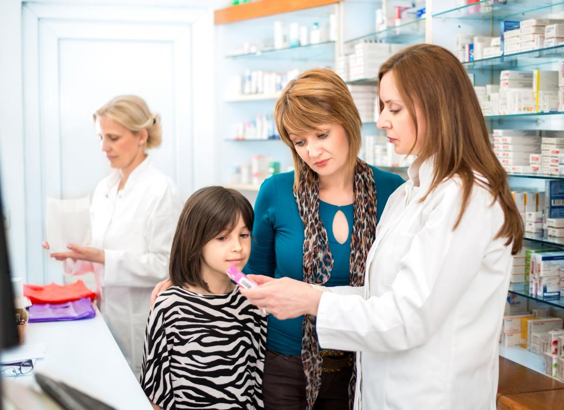 mother and young daughter being shown medication by pharmacist