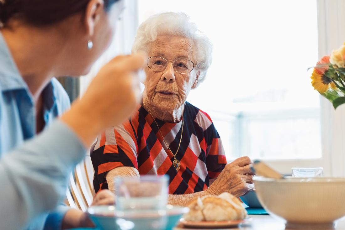 Senior person eating at table and talking.