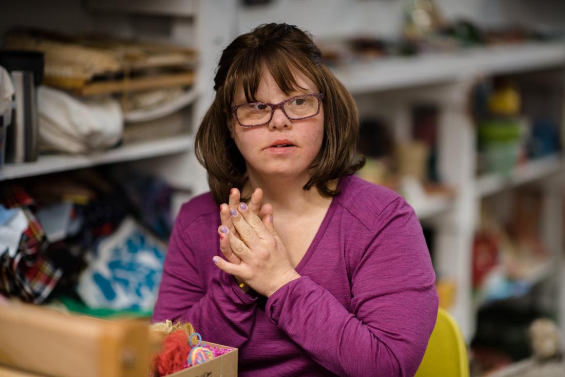 Woman with down syndrome and learning disability sitting alone.