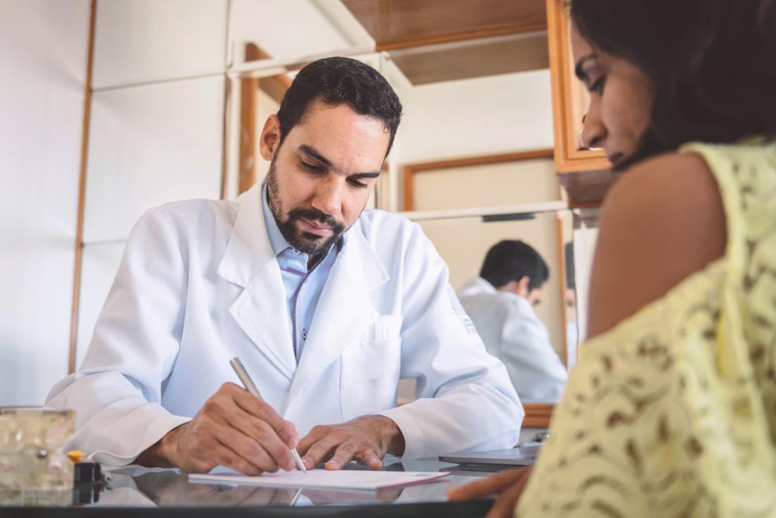 doctor writing a prescription to a patient