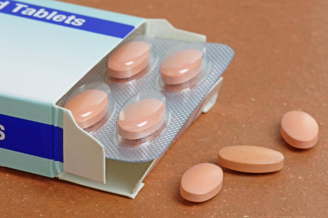 A packet of statins, with the front off and three tablets lying on a table. 