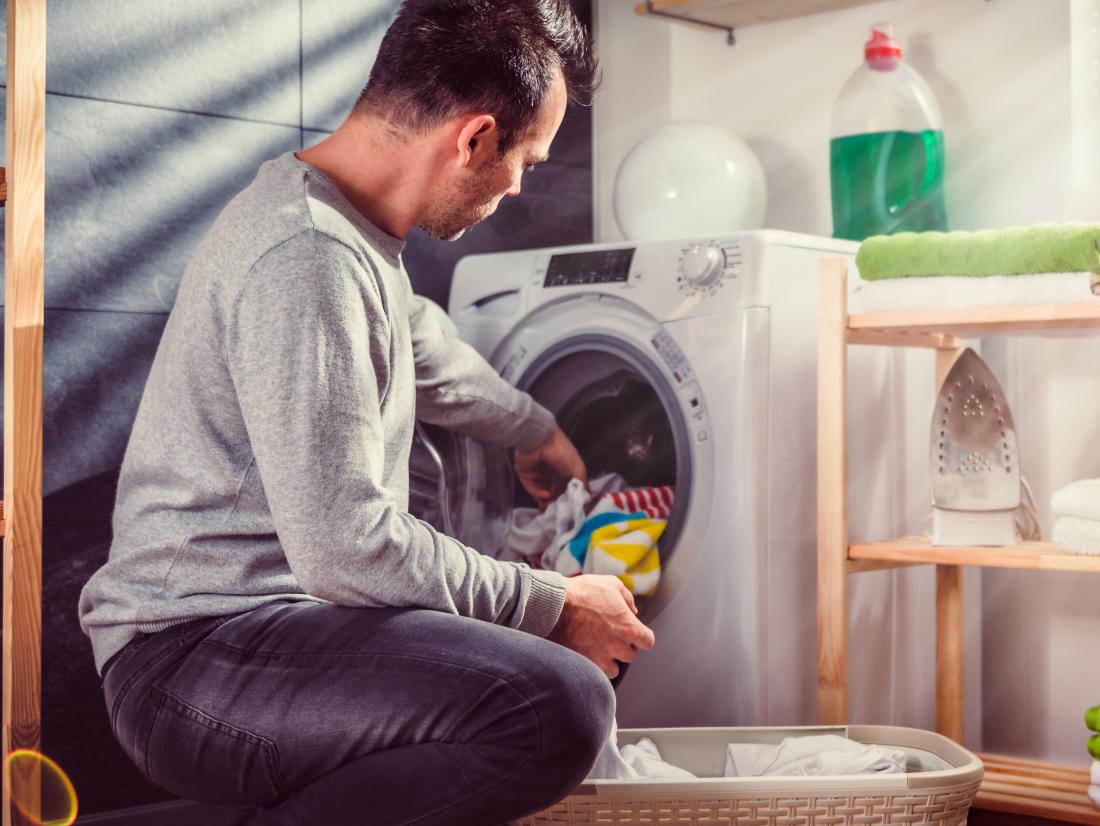 a man putting laundry in a washing machine. 