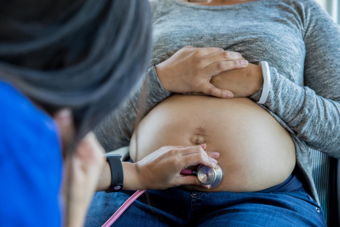 a midwife checking a woman's pregnant belly.