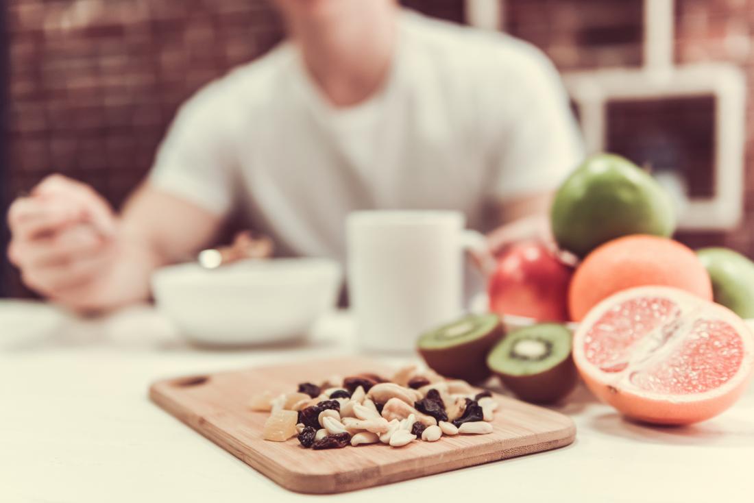 nuts in the foreground, a man eating and fruit in the background