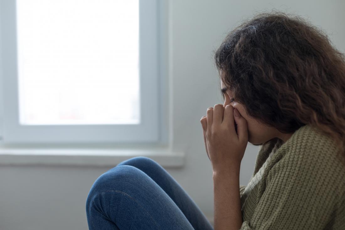 a woman having a panic attack next to a window. 