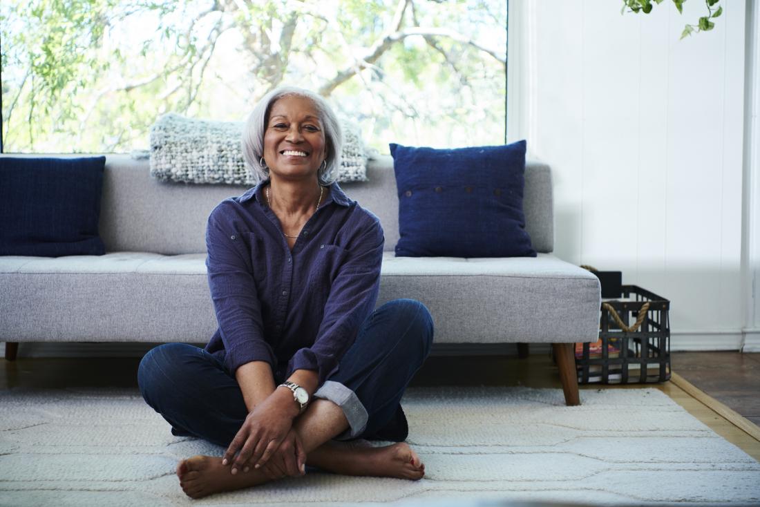 smiling older woman sitting cross legged on the floor