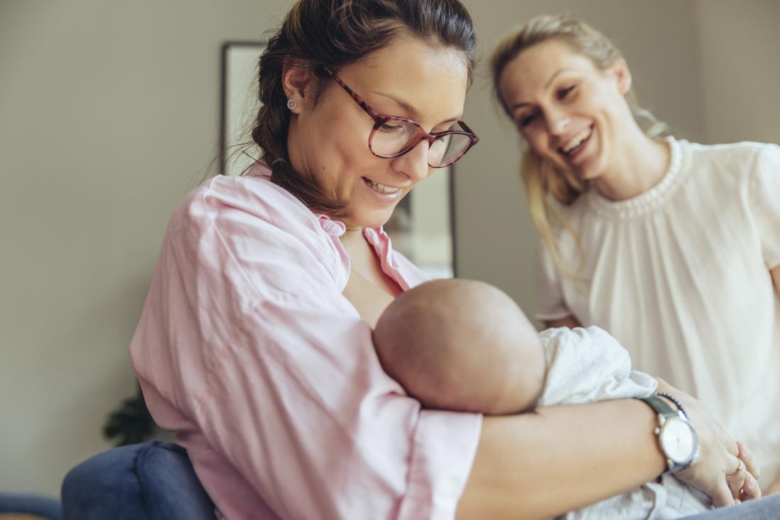 two woman watching their baby breastfeed. 