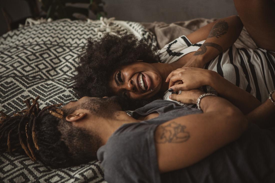 a smiley couple laughing in bed.