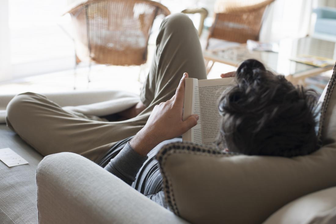 person relaxing on sofa reading book