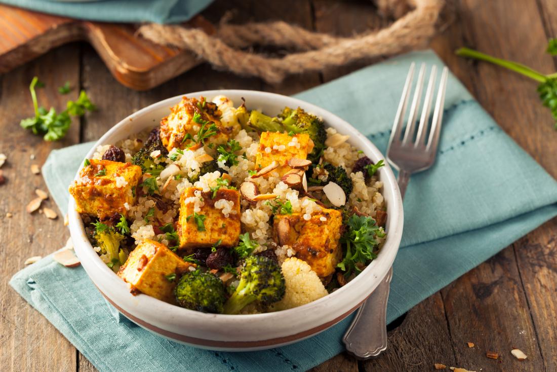 homemade quinoa tofu bowl with broccoli vegan meal on wooden table with blue rustic napkins