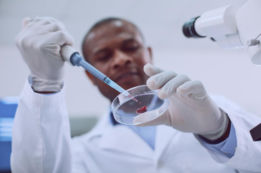 researcher analyzing a drop of blood in a petri dish