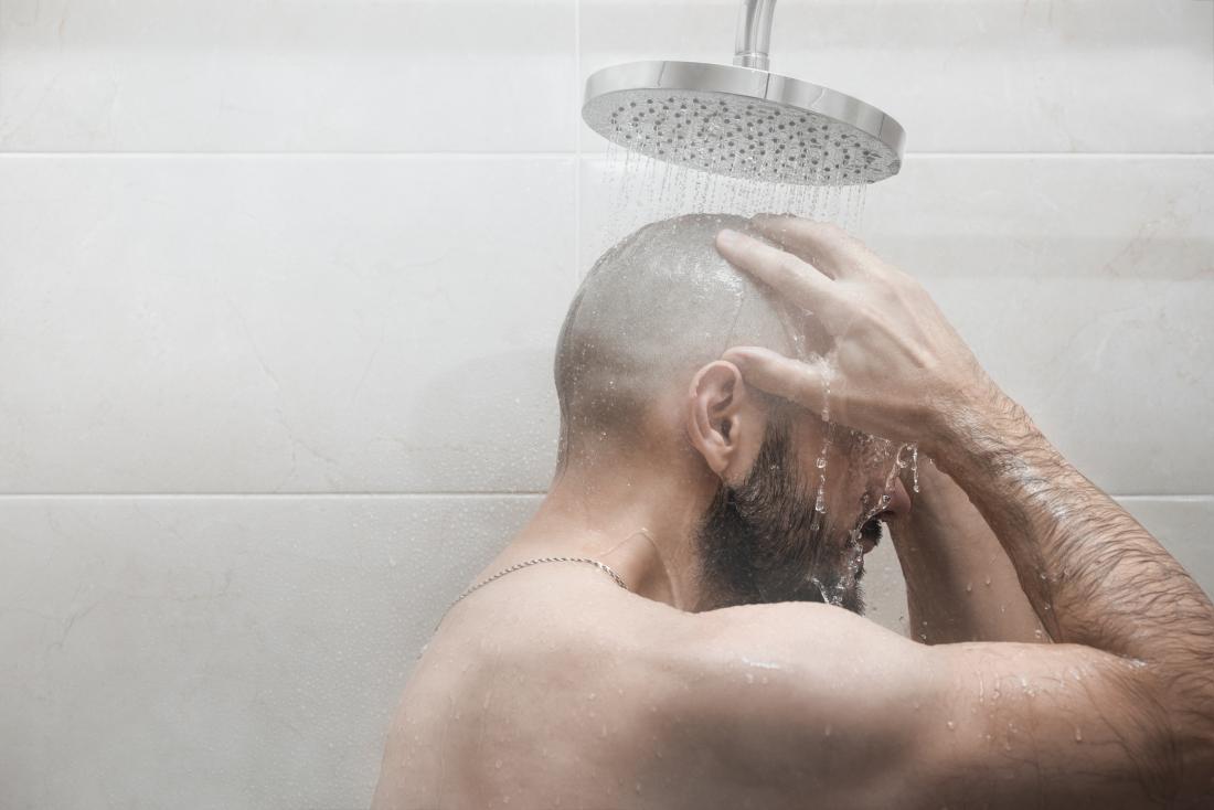 a bald man having a shower.