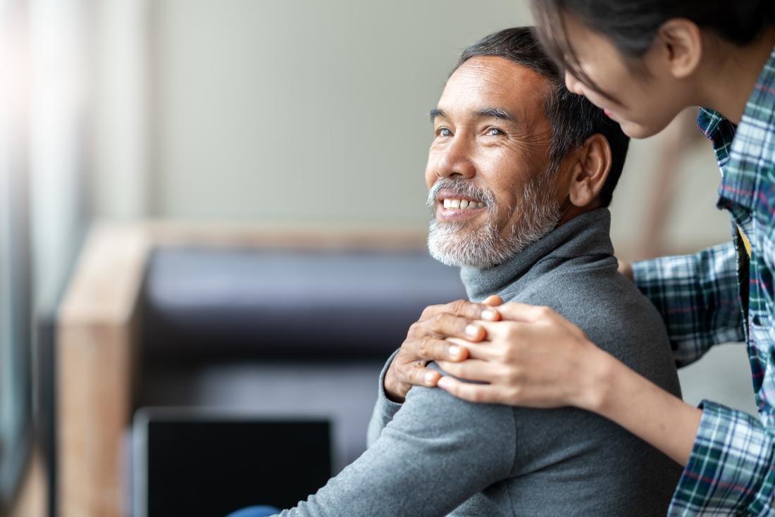 a man smiling when his daughter greets him with a touch on the shoulder. 