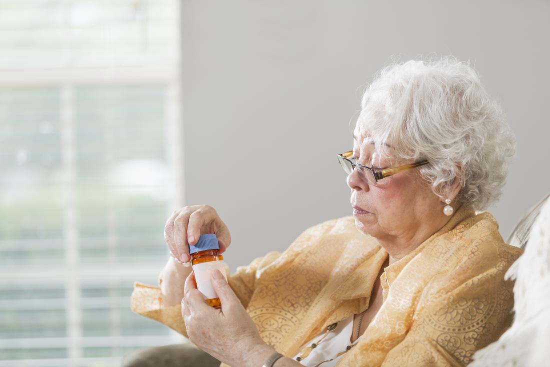 senior woman holding bottle of tablets