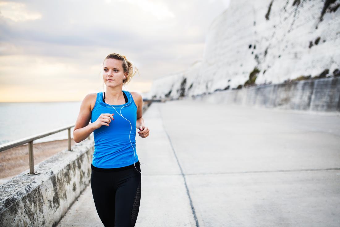 a woman running along aside a cliff side walk. 