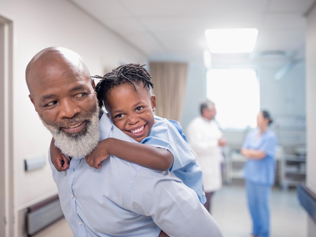 a child climbs on his fathers back whilst in hospital. 