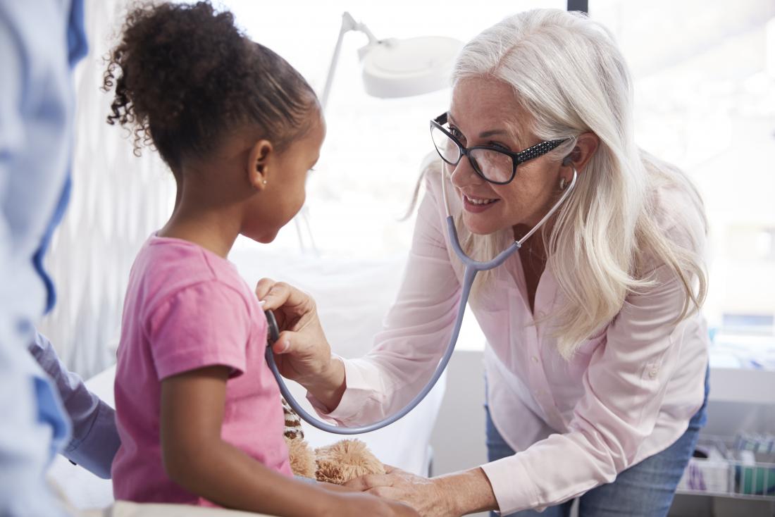 a doctor checks a young child chest 