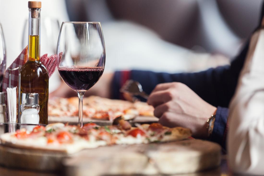 a woman enjoying wine with a pizza