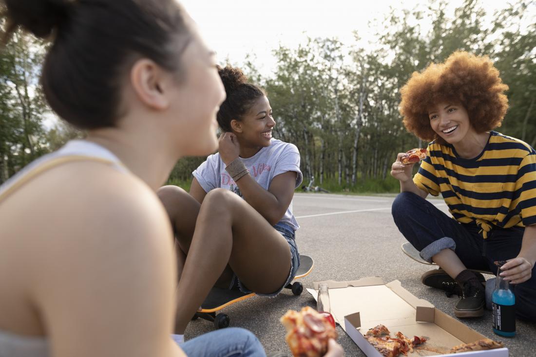 Group of young women discussing types of vaginas sitting down and eating pizza.