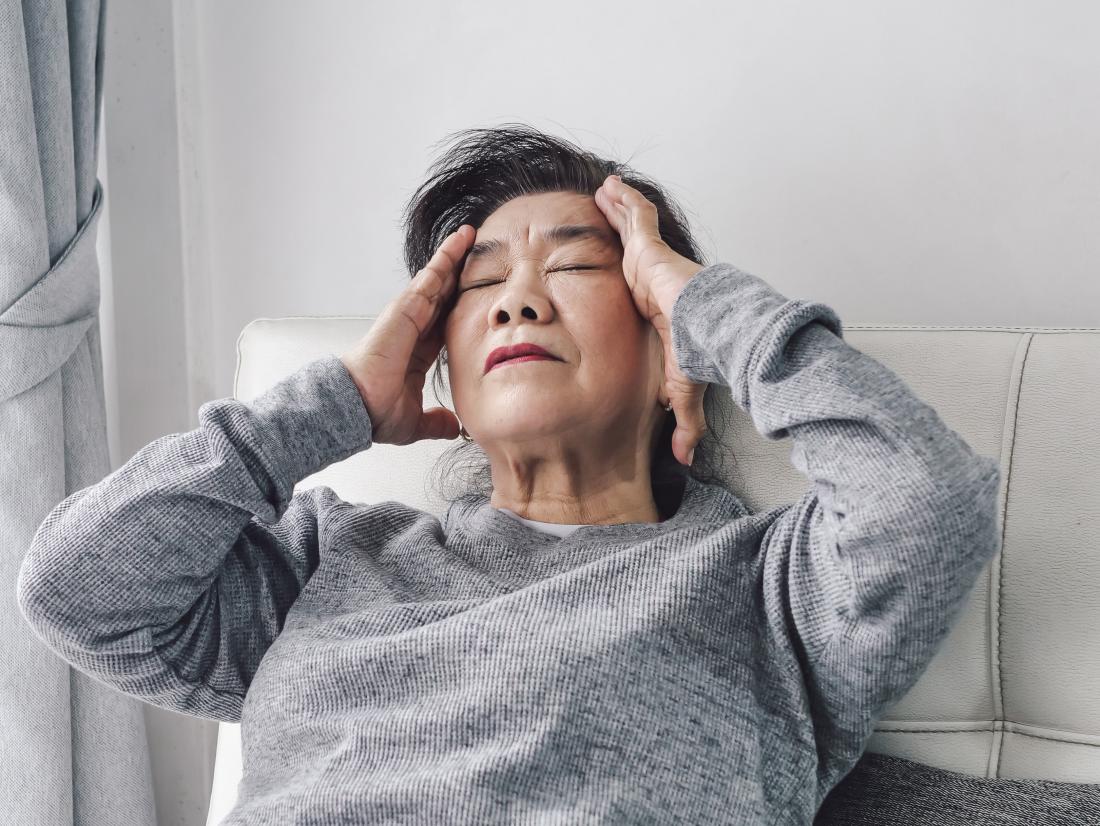 an elderly asian lady experiencing a headache. 