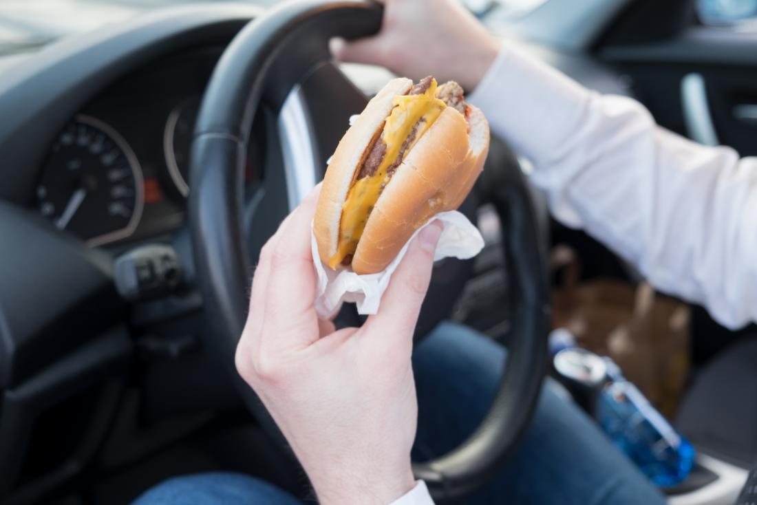 a woman eating a burger in a car. 