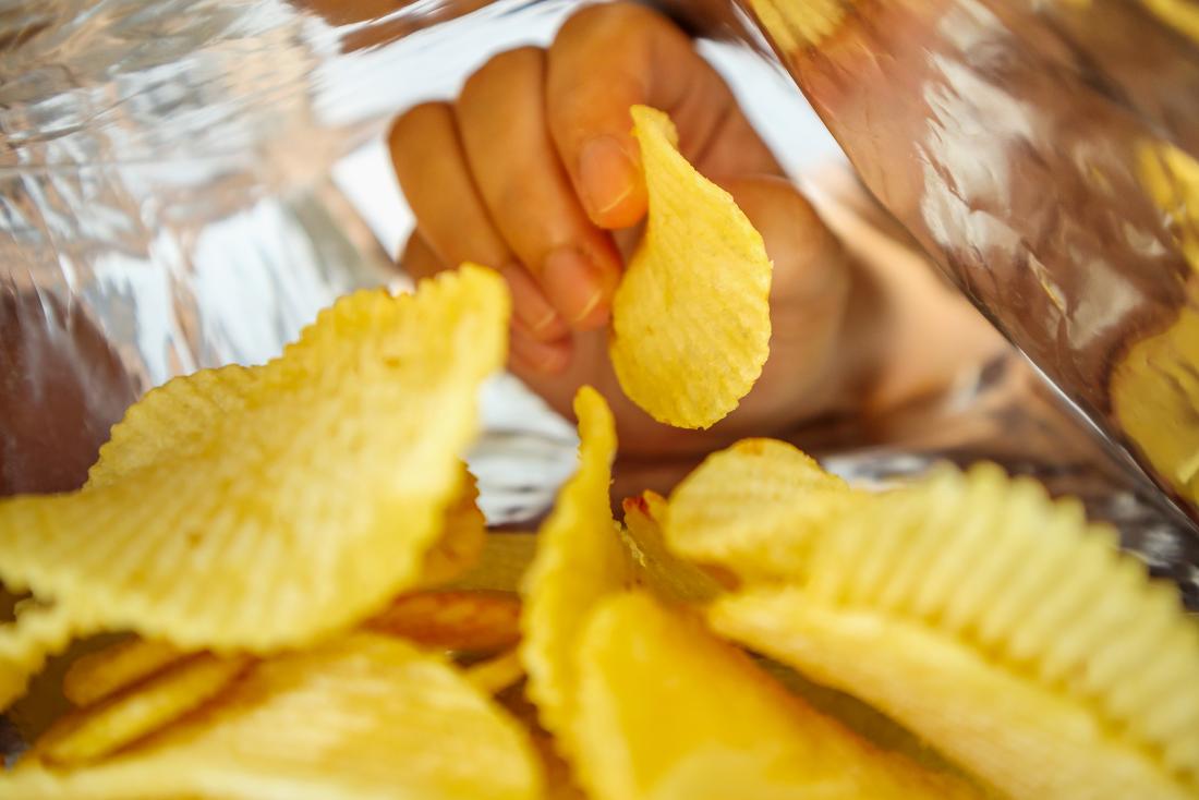 a hand in a packet of crisps.