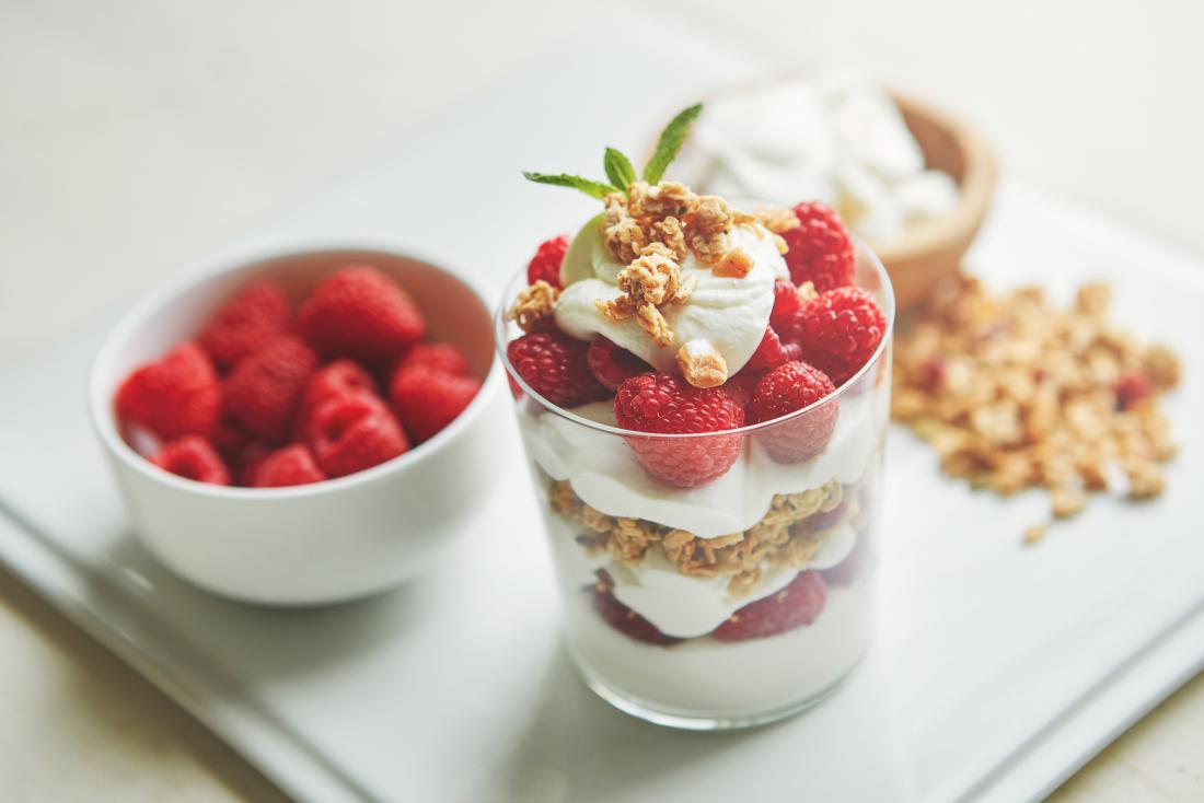 Raspberries, muesli, and yoghurt in cup for healthy breakfast or snack
