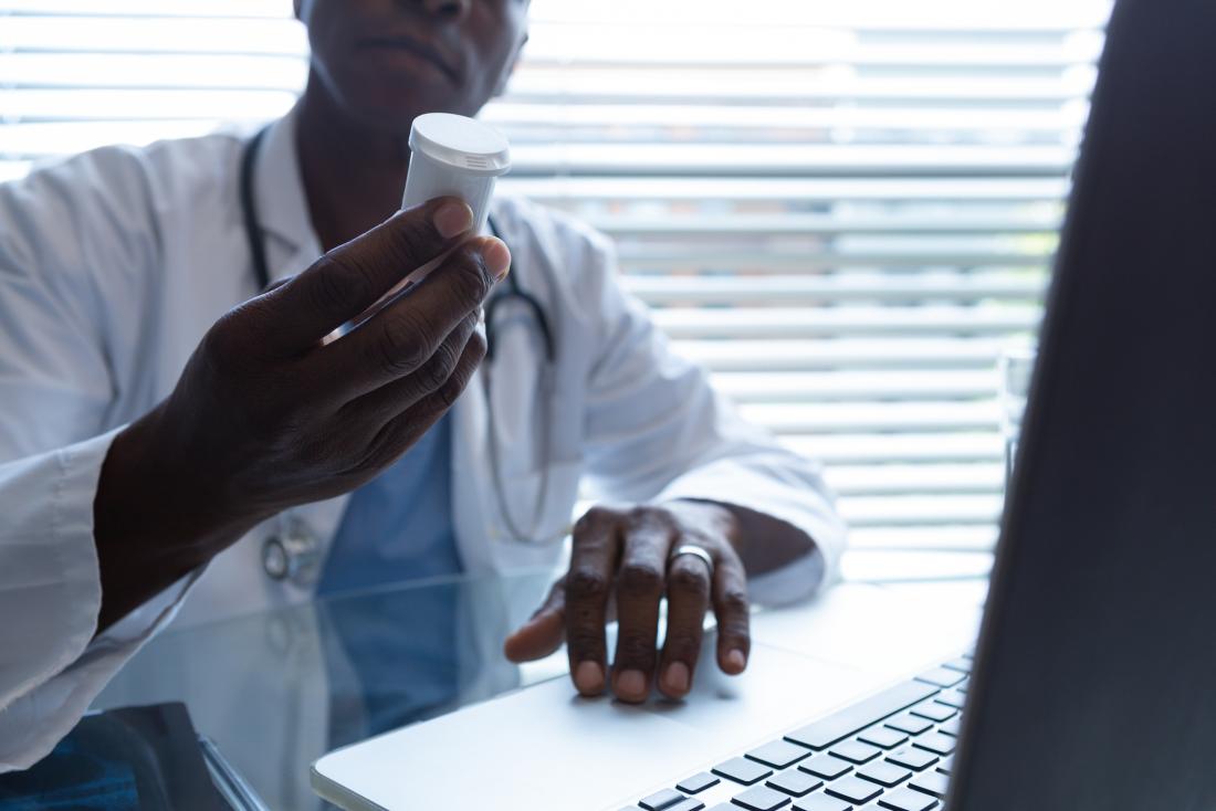 doctor looking at bottle of medication closely