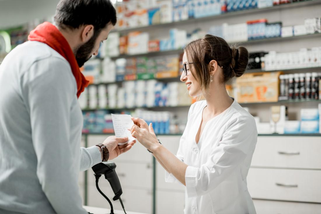 a man looks at his prescription with a pharmacist