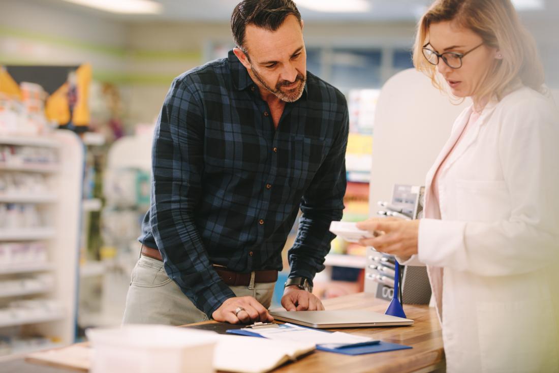 a man talks to a pharmacist about his prescription. 