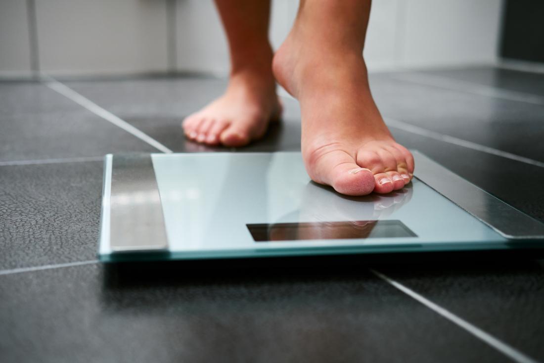 person stepping on weighing scales