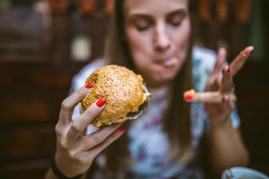 a woman eating a messy cheese burger.