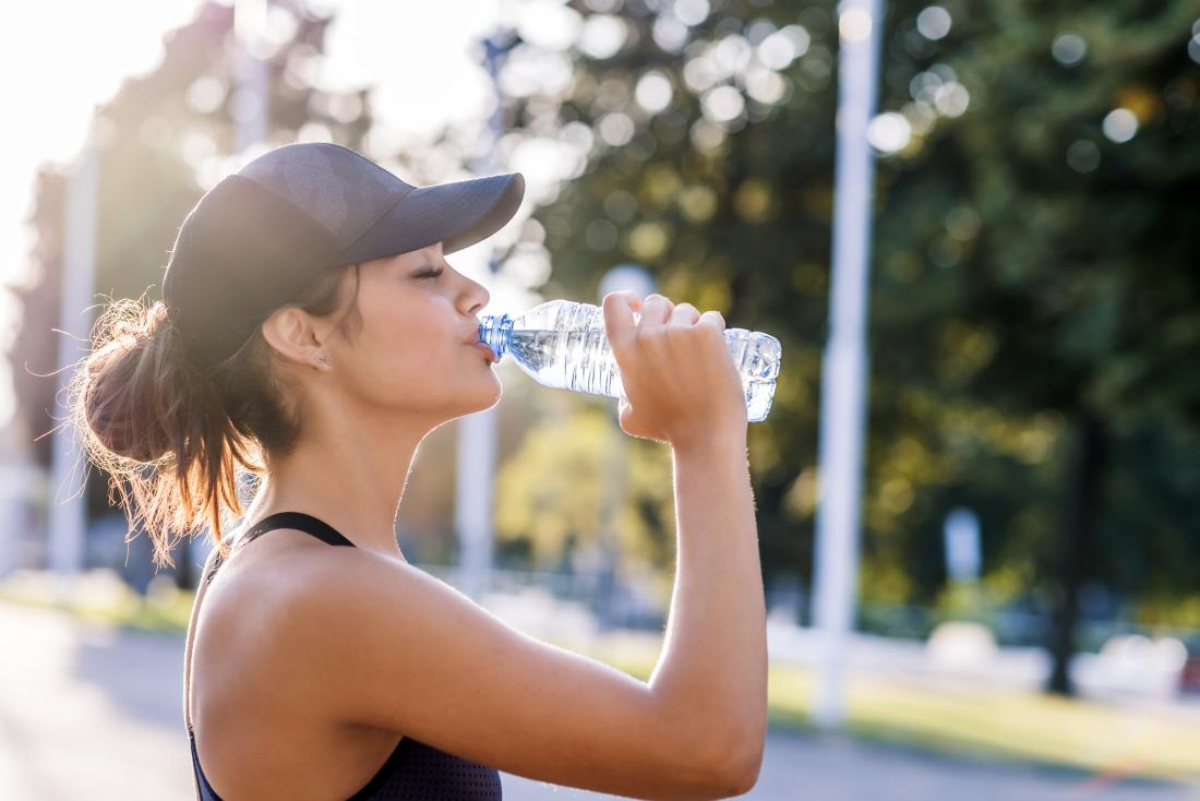 a woman hydrating with water during exercise.