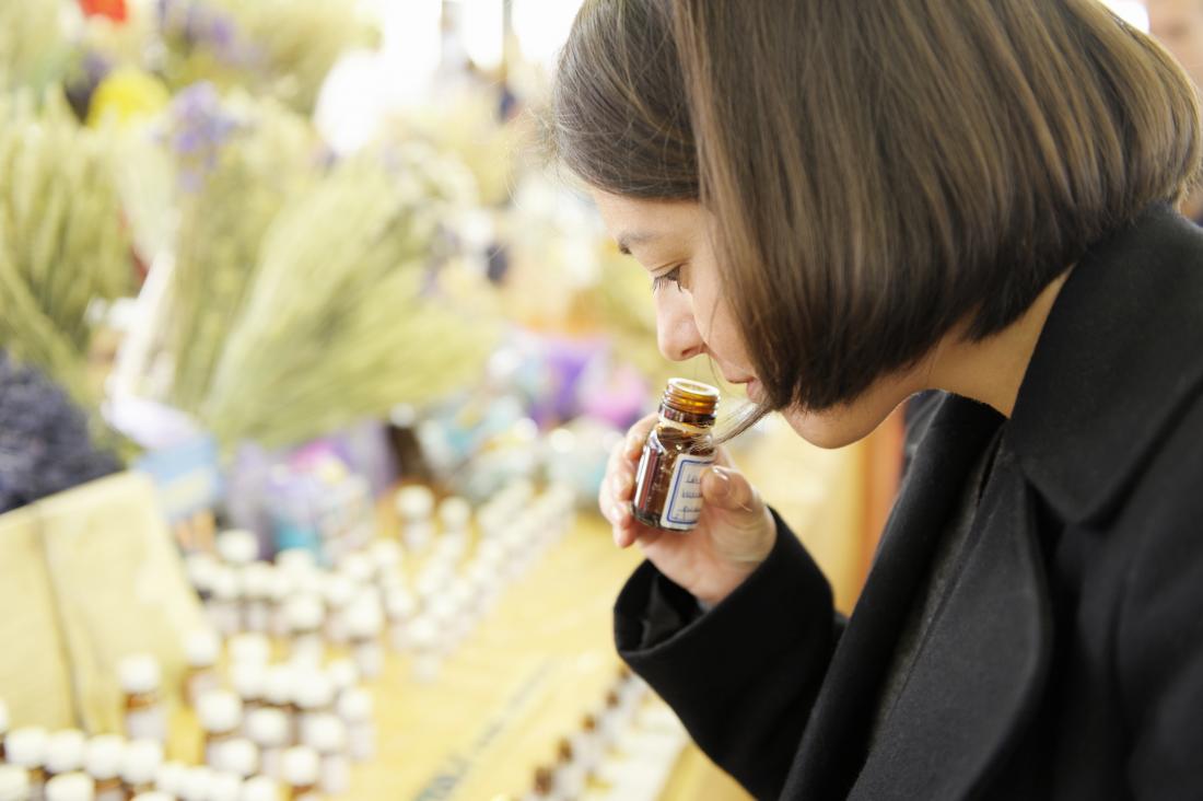 a woman smelling an essential oil at a market stall