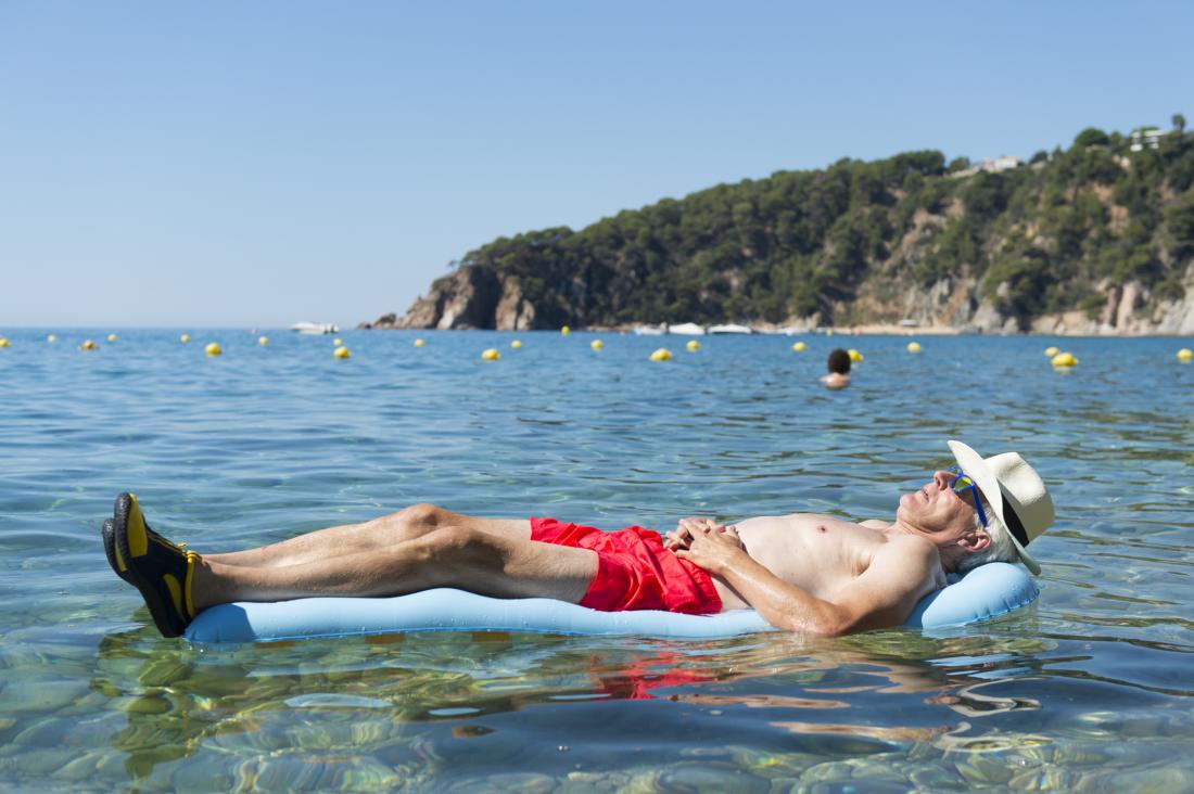 an older man lying on a lido in the sea. 