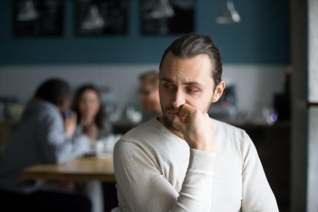 a man feeling lonely as he sees people speaking at a table near him.