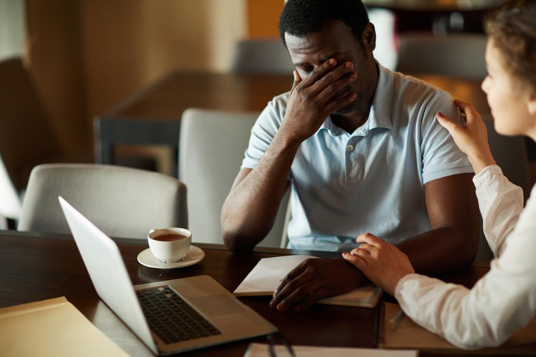 man looking stressed at work, being consoled