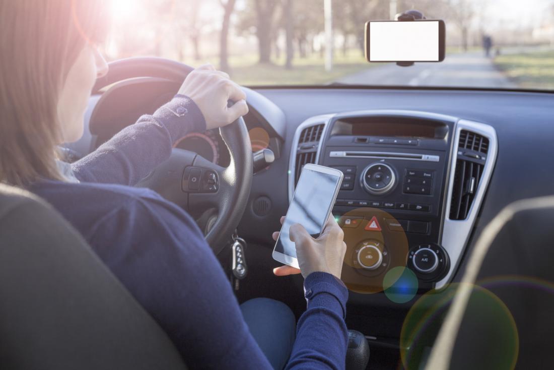 woman looking at her phone while driving