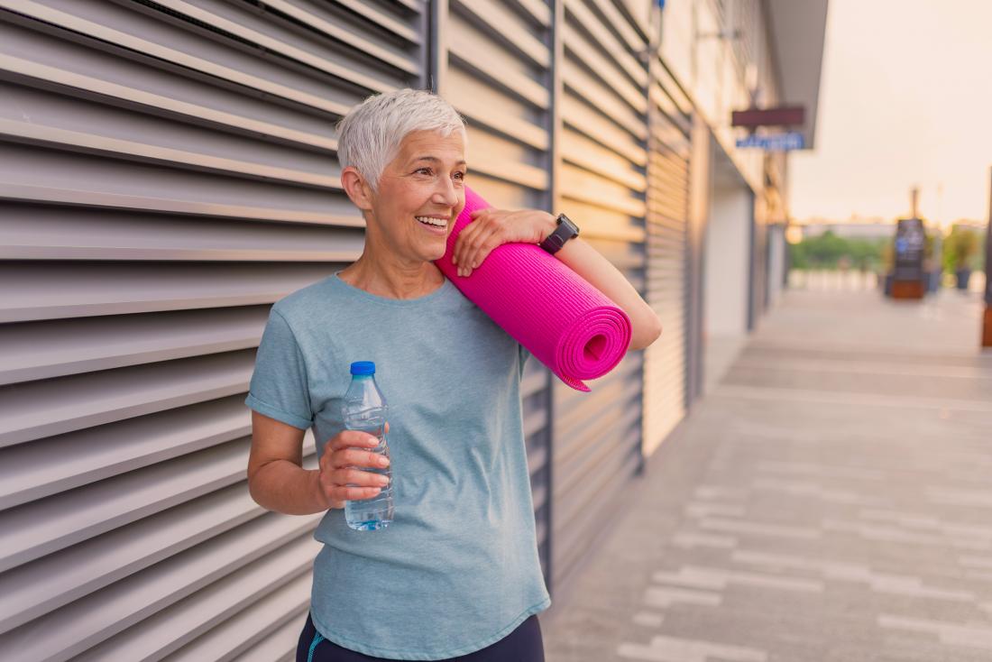 a woman holding a yoga matt and a water bottle 