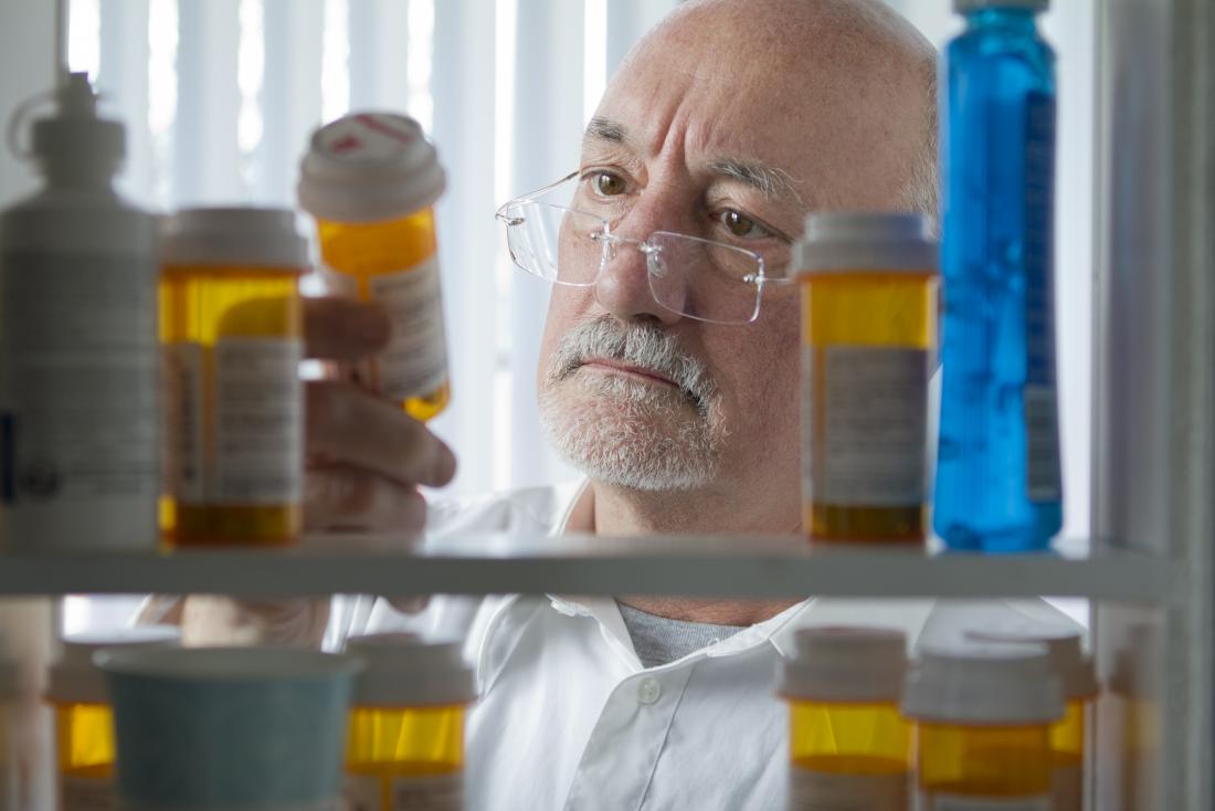 Senior man looking at prescription drugs in a medicine cabinet. 