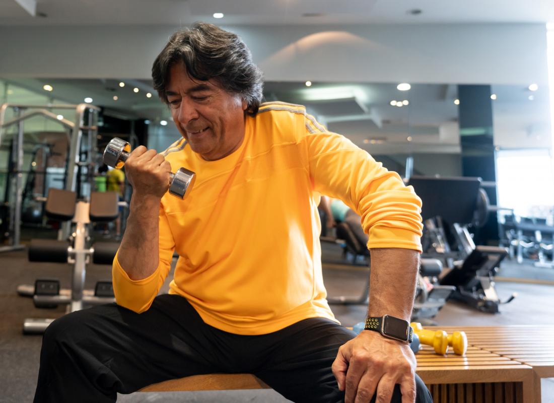 A Senior man exercising at the gym with free weight